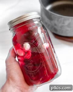 Small Batch Pickled Beets in a mason jar against a white background, filled with brine and ready for refrigeration.