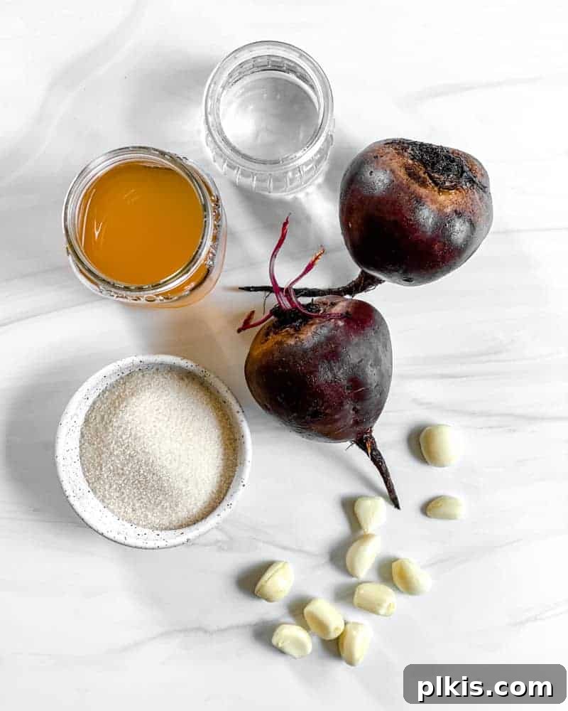 Ingredients laid out for Small Batch Pickled Beets against a white background, including beets, apple cider vinegar, water, sugar, and garlic.