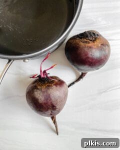 Two beets with a pot against a white background, ready for cooking.