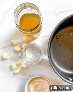 Ingredients for Small Batch Pickled Beets brine, including apple cider vinegar, water, sugar, and garlic, in a pot against a white background.