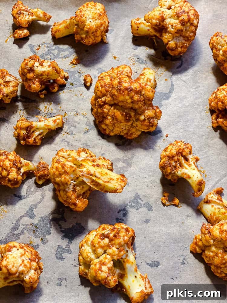 Fiery Roasted Cauliflower 6 Process shot showing spicy cauliflower florets spread in a single layer on a baking sheet.