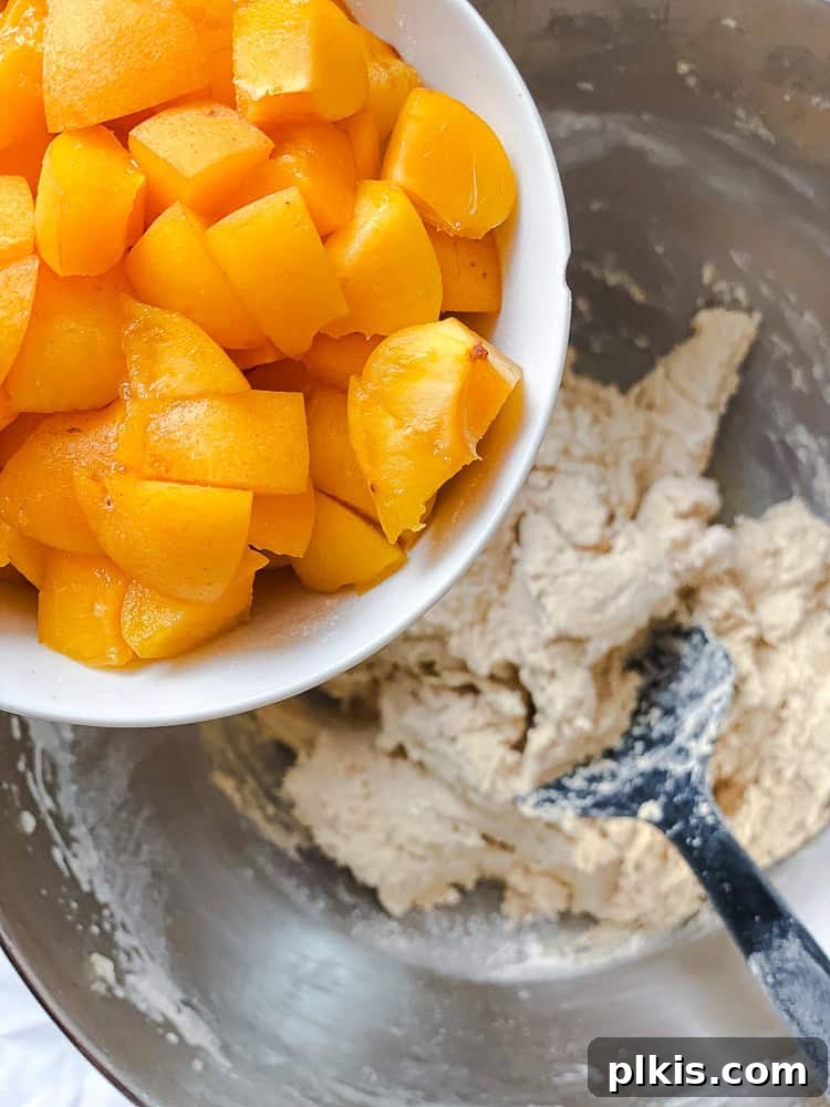 Golden Apricot Delights 8 Process shot showing diced fresh apricots being carefully folded into the prepared cookie dough with a spatula.