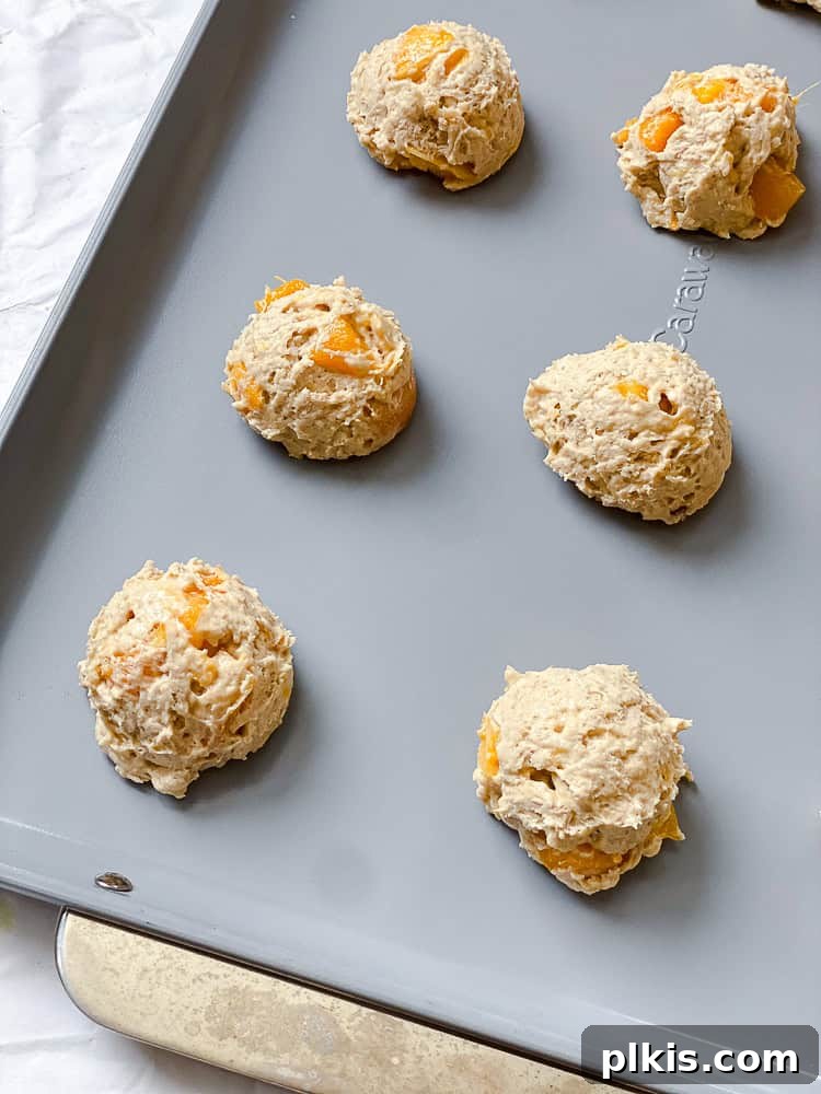 Golden Apricot Delights 9 Process shot displaying perfectly scooped, unbaked apricot cookie dough mounds evenly spaced on a parchment-lined baking sheet, ready for the oven.