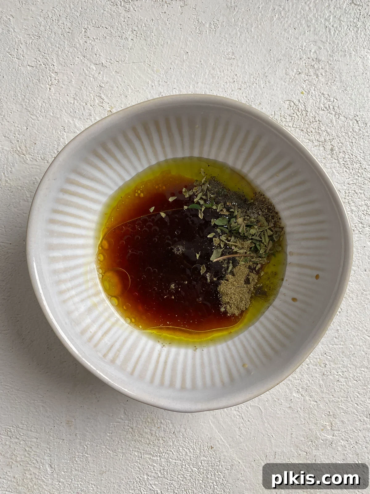 Berry Burst Kale Salad 6 process of adding Strawberry Kale Salad dressing ingredients into one white bowl against a light background