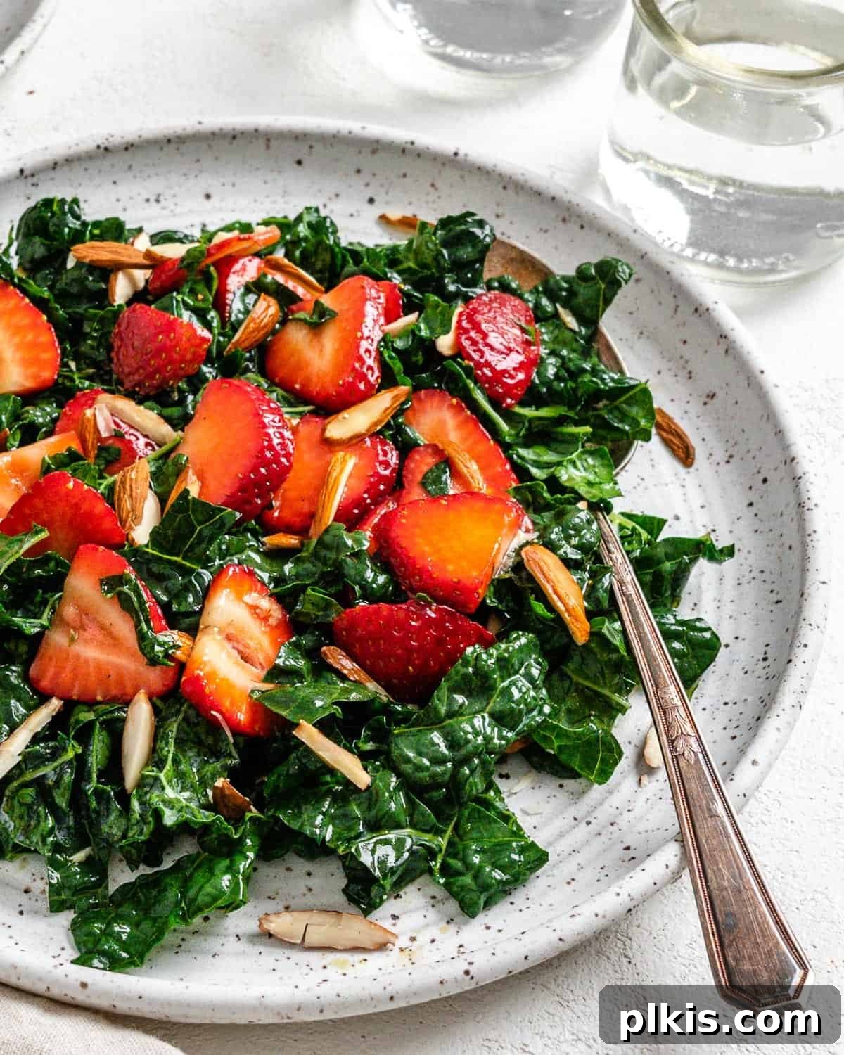Berry Burst Kale Salad 9 completed Strawberry Kale Salad on a white plate against a white surface, close-up shot