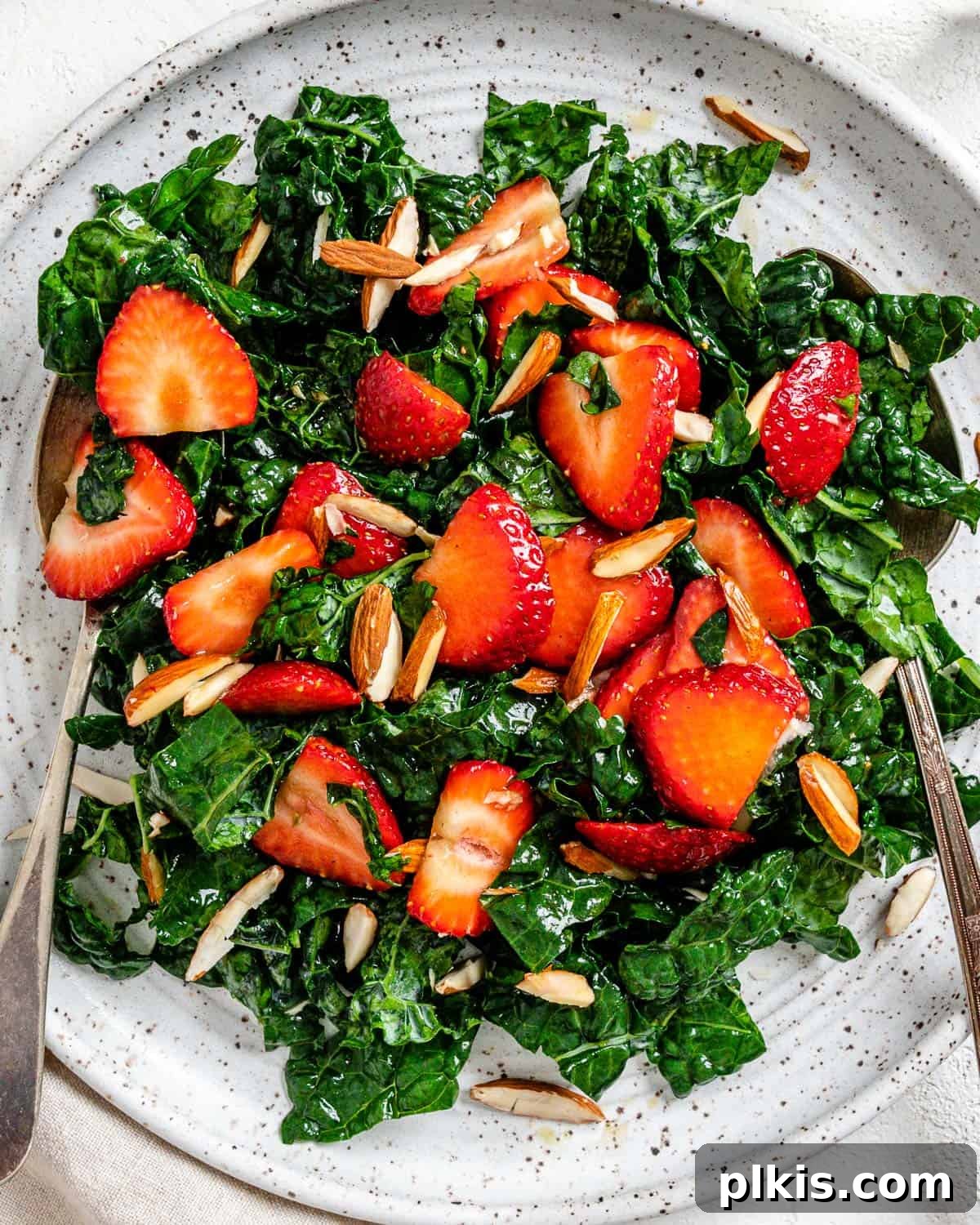 Berry Burst Kale Salad 10 completed Strawberry Kale Salad on a white plate against a white surface, showcasing its vibrant ingredients