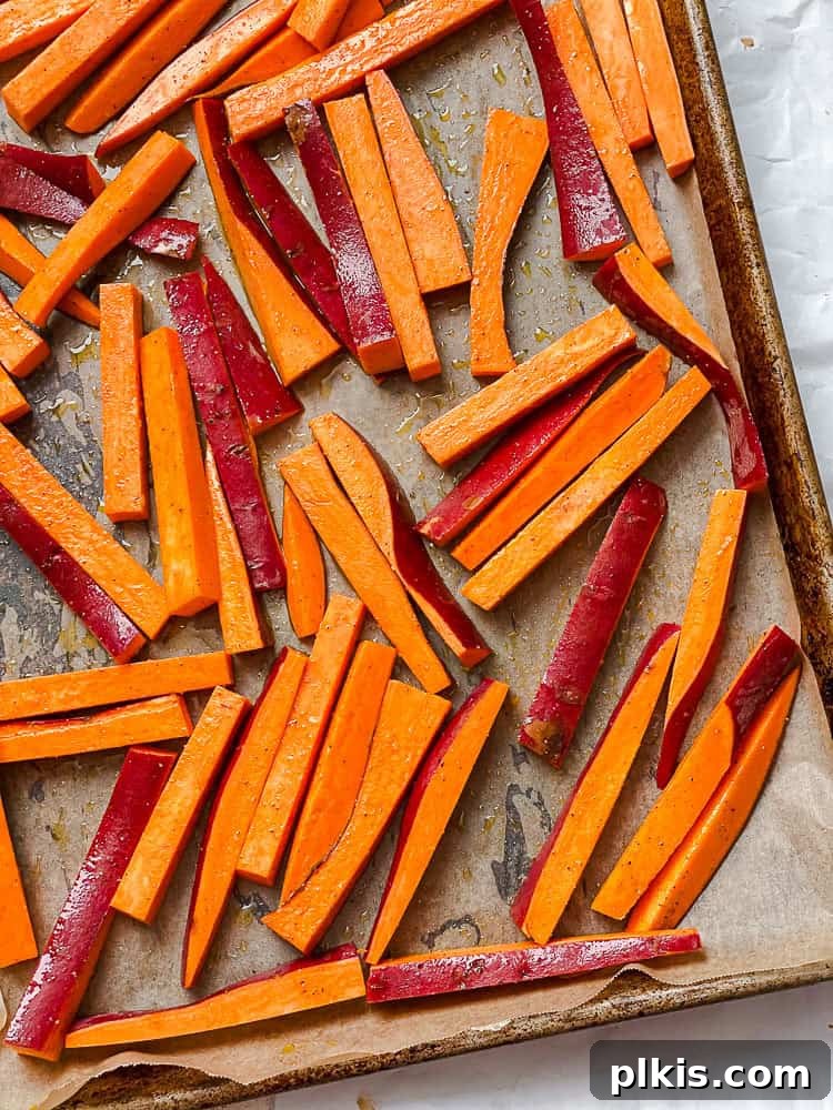 Vibrant Sweet Potato Kale Salad 4 Process shot showing chopped sweet potatoes seasoned on a baking tray.