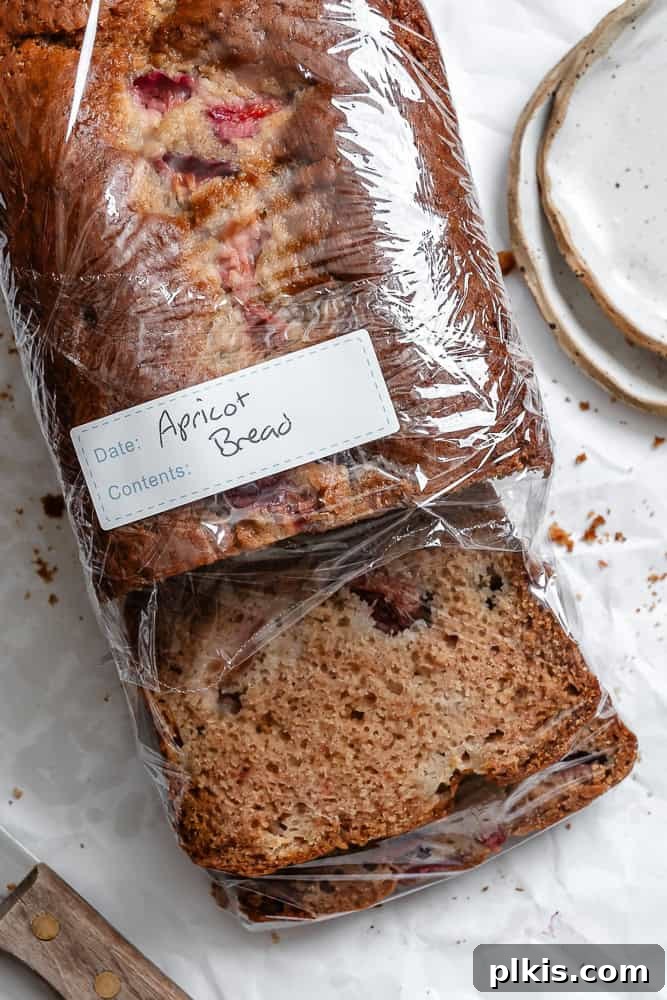 Golden Apricot Quick Bread 9 Completed Easy Apricot Bread on a white surface, half-wrapped in plastic wrap, demonstrating proper storage.