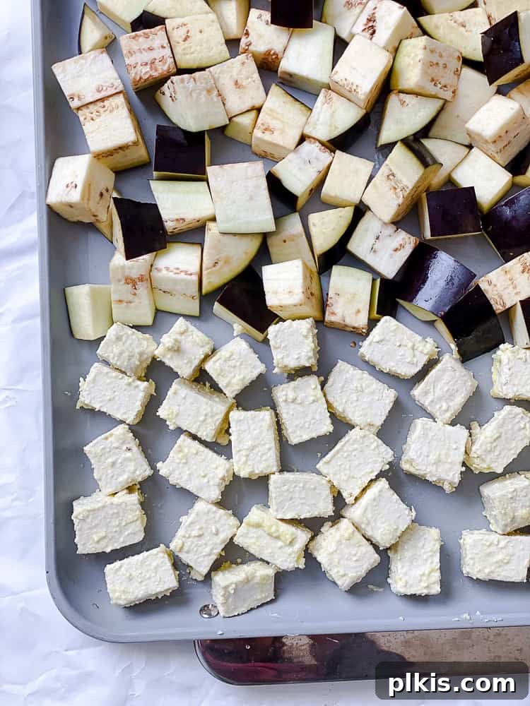 Sweet Chili Glazed Eggplant and Tofu 6 A process shot showing cornstarch-coated tofu cubes spread evenly on a baking sheet, ready for the oven.