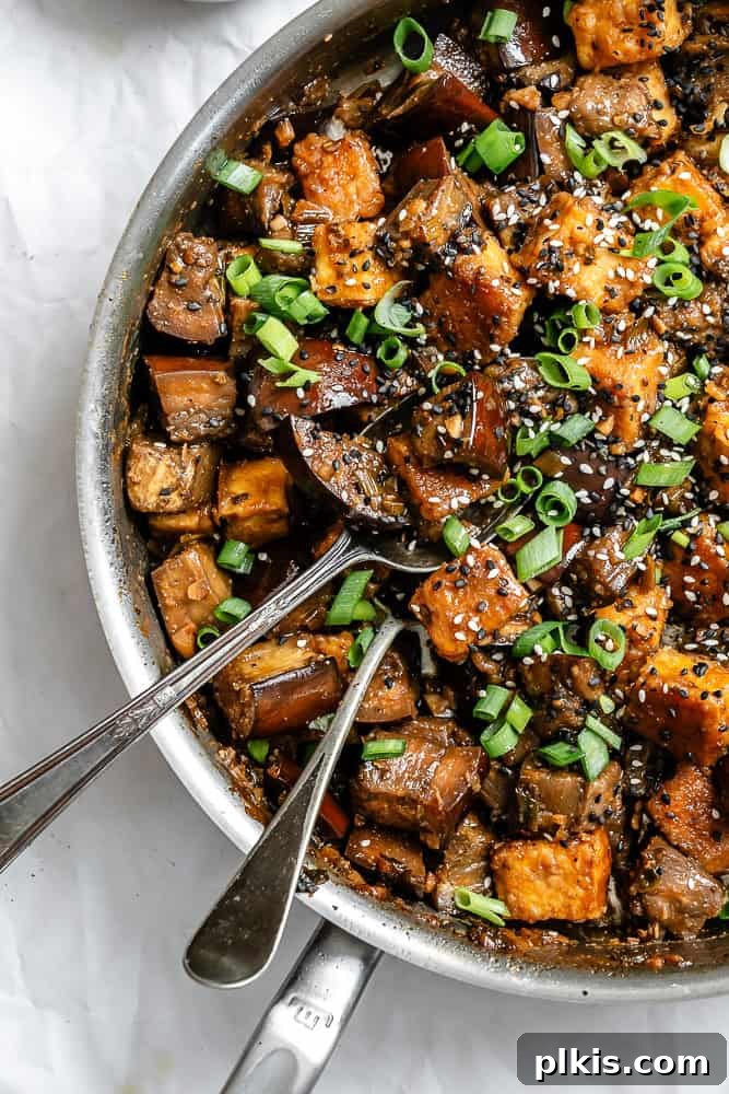 Sweet Chili Glazed Eggplant and Tofu 9 A delicious plate of Sticky Eggplant and Tofu garnished with green onions and sesame seeds, ready to be enjoyed as a meal.