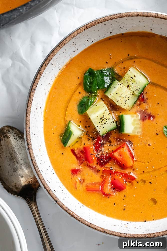 Summer Melon Chill 8 A beautifully presented bowl of Watermelon Gazpacho, garnished with fresh basil, finely diced cucumbers, and red peppers, ready to be enjoyed.