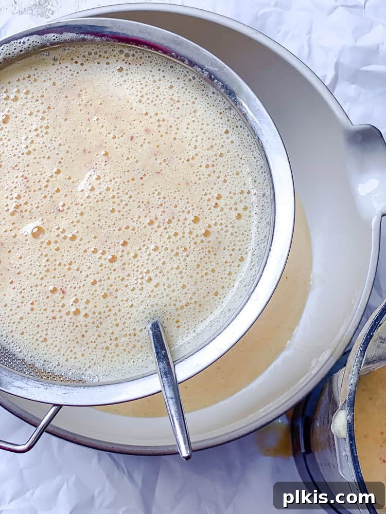 Golden Peach Lemonade 6 straining peach lemonade through a fine mesh strainer into a bowl.