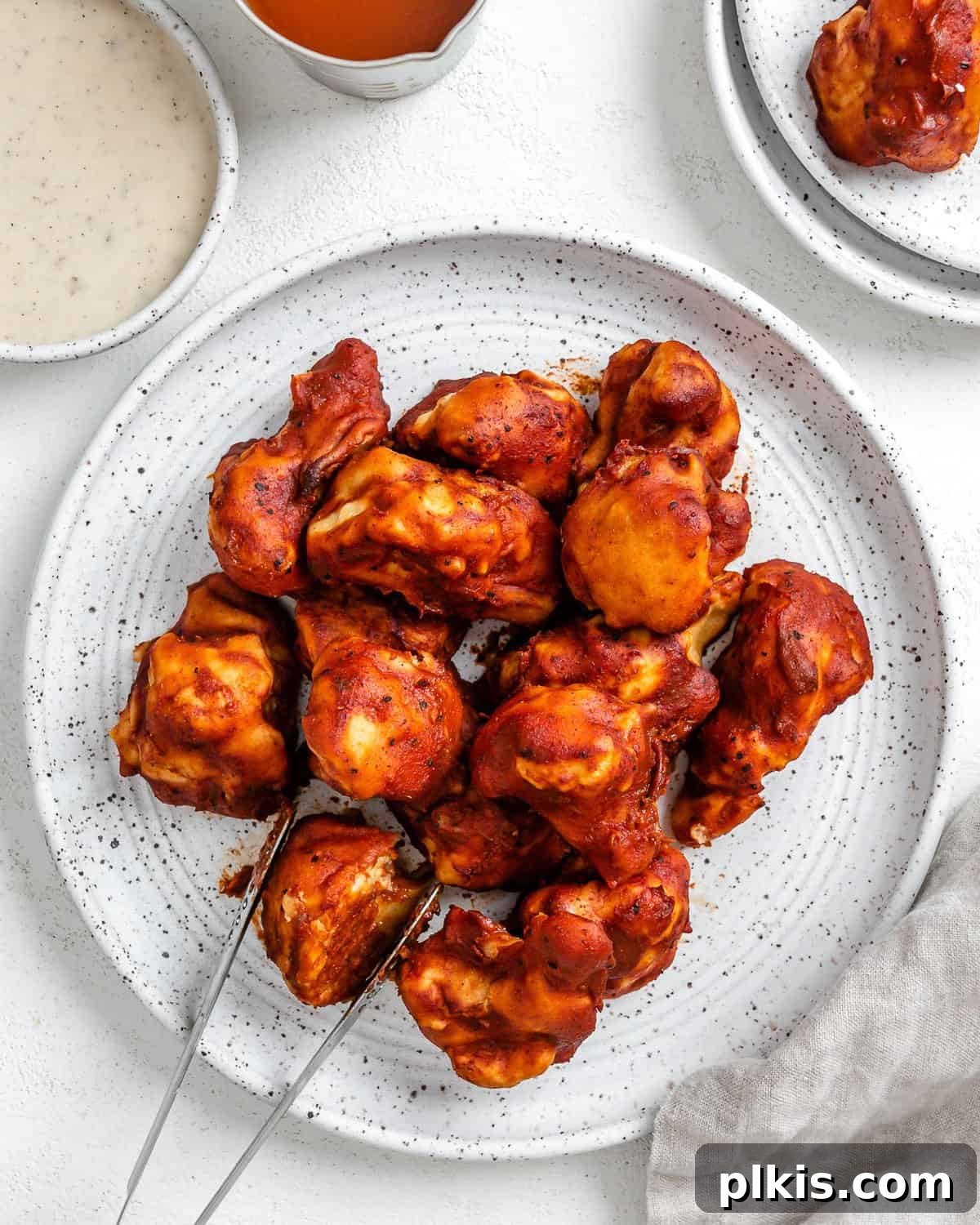 Completed BBQ Cauliflower Wings plated on a white plate with a bowl of sauce in the background