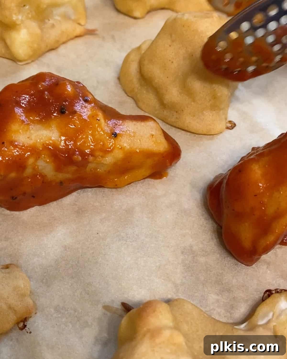 Process shot of placing bbq cauliflower wings onto parchment paper