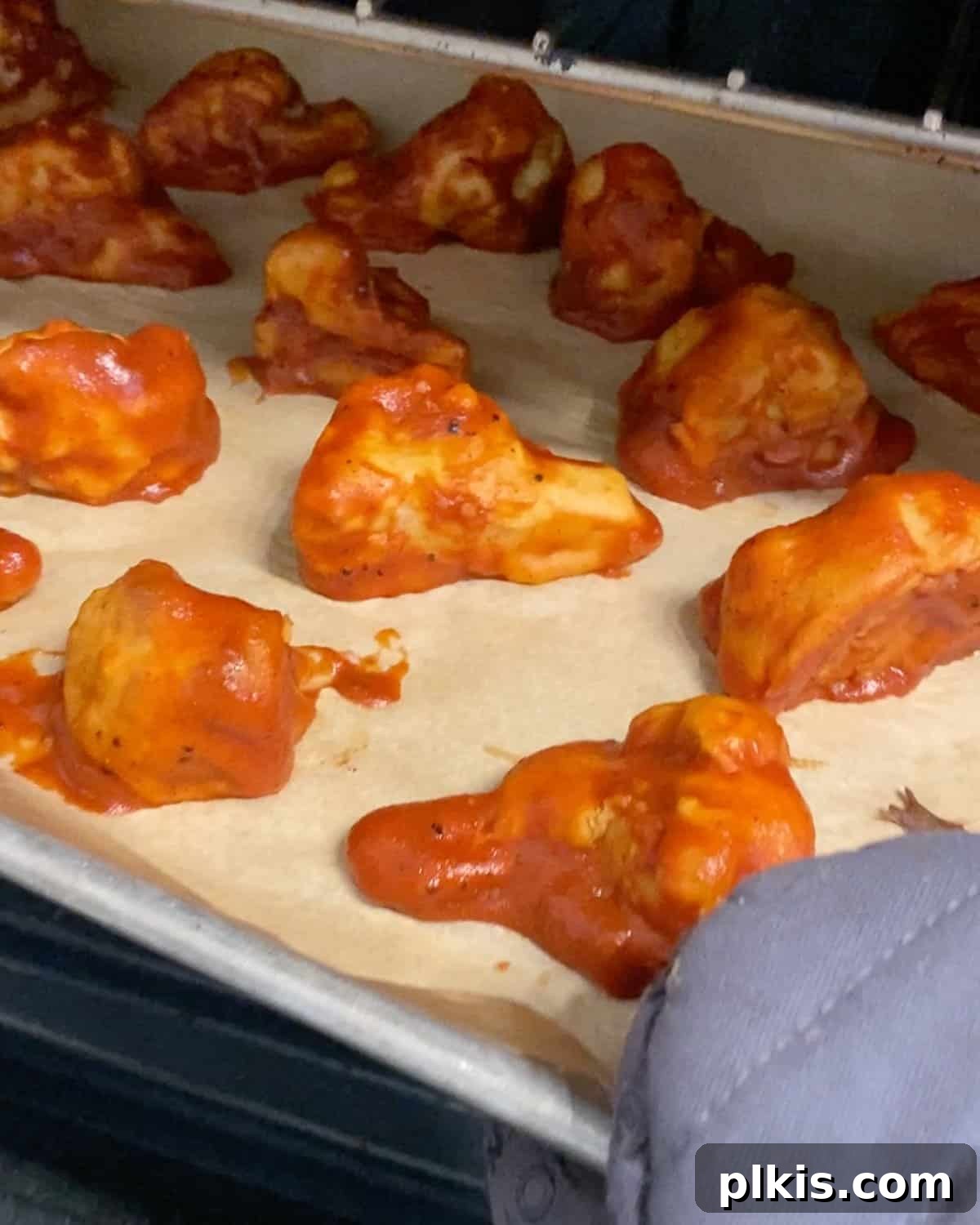 Process shot of placing bbq sauce covered cauliflower in oven