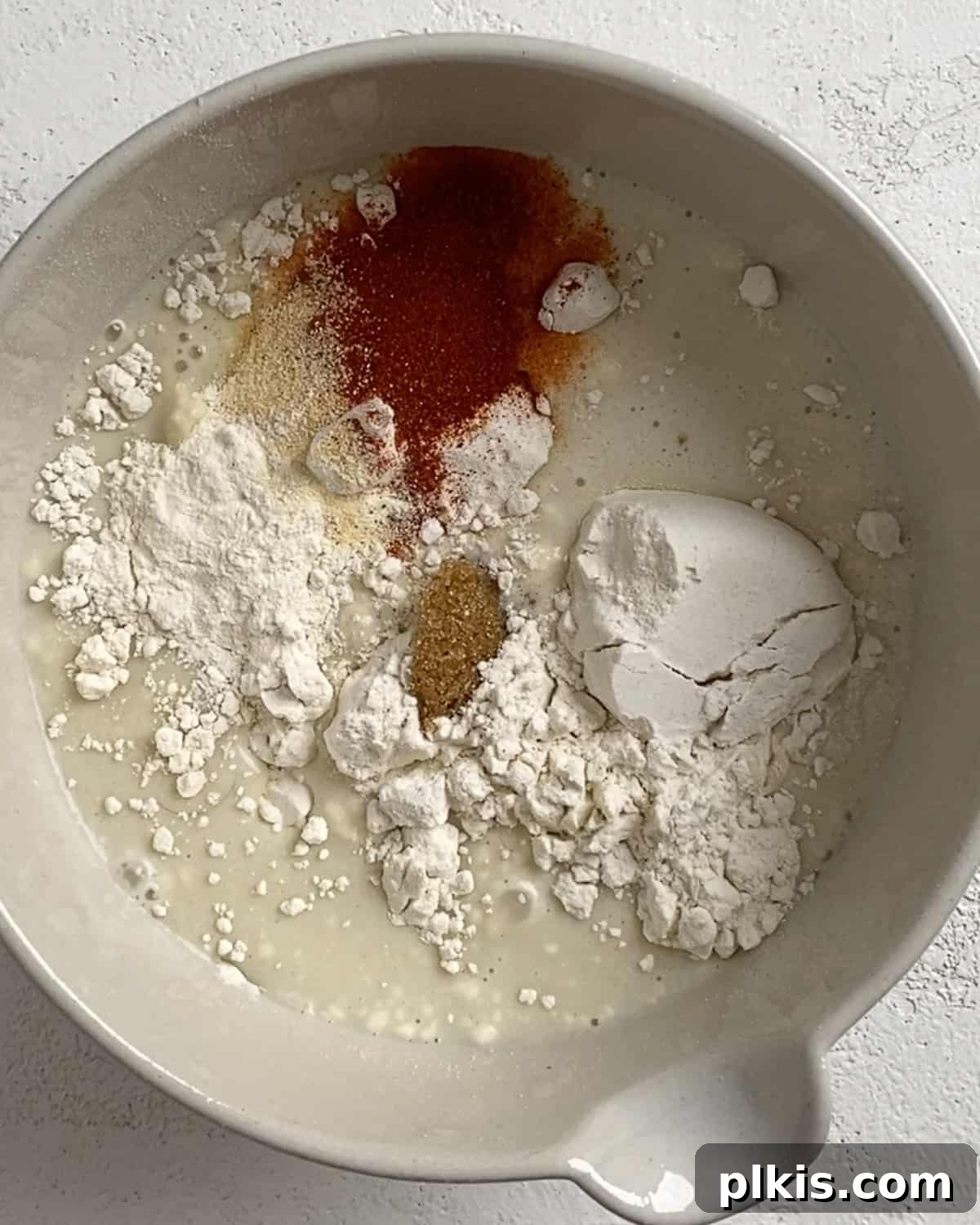 Process shot of adding ingredients to cauliflower batter