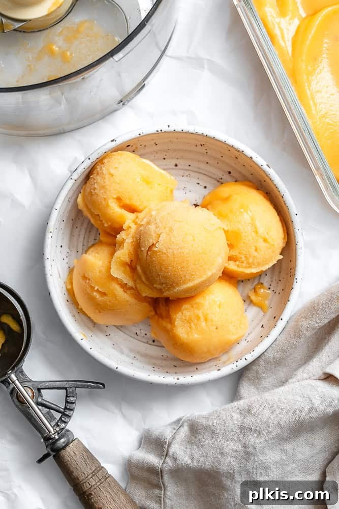 Golden Peach Dream 2 Five scoops of homemade peach sorbet in a pristine white bowl, garnished with a fresh mint leaf, perfectly showcasing its vibrant color and smooth texture. The backdrop suggests a bright, sunny atmosphere, hinting at a perfect summer dessert.