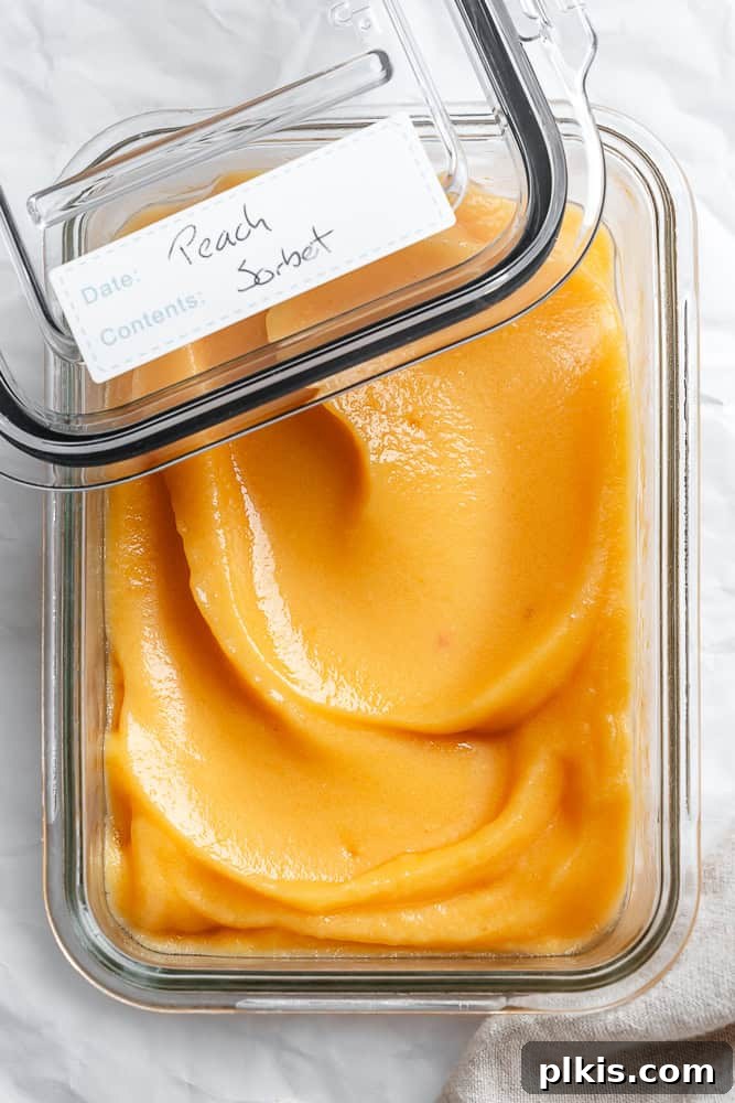 Golden Peach Dream 8 Freshly made peach sorbet stored in a clear glass airtight container in the freezer, ready for future enjoyment.