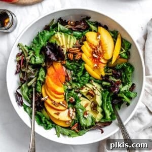close up on a peach salad in a large white bowl.