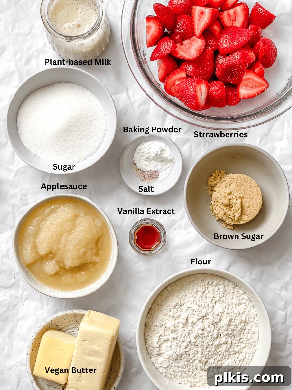 Strawberry Crown Cake 3 ingredients for Strawberry Upside Down Cake measured out on a white surface, including fresh strawberries, flour, sugar, and vegan butter