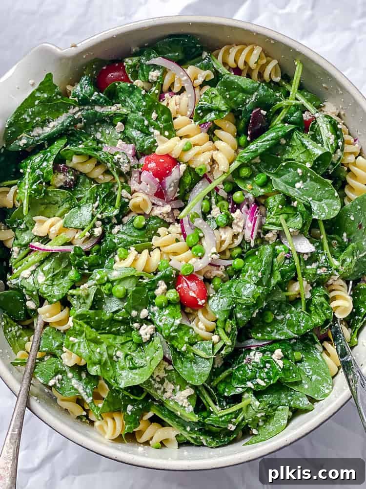 spinach pasta salad in a large white bowl.