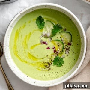 A vibrant bowl of Cucumber Gazpacho, garnished with fresh herbs and a drizzle of olive oil.