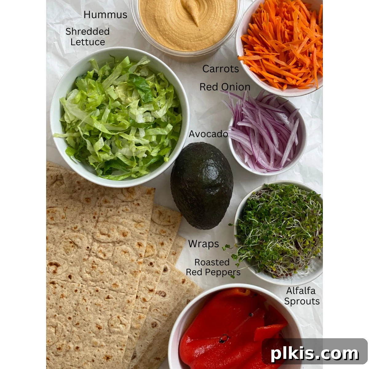 Effortless Hummus Roll Ups 3 Carefully measured ingredients for Roasted Red Pepper Wraps, including fresh vegetables, hummus, and tortillas, neatly arranged on a white backdrop, ready for assembly.