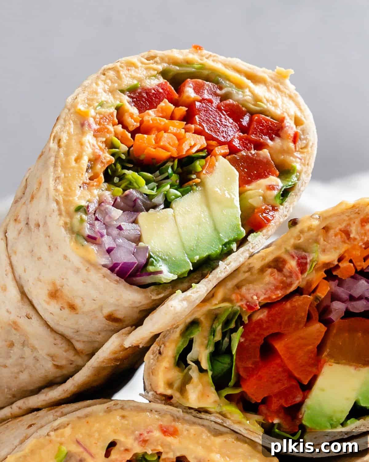 Effortless Hummus Roll Ups 6 Two perfectly rolled and sliced Easy Hummus Tortilla Wraps presented on a clean white surface, highlighting their attractive cross-section and ready-to-eat appeal.