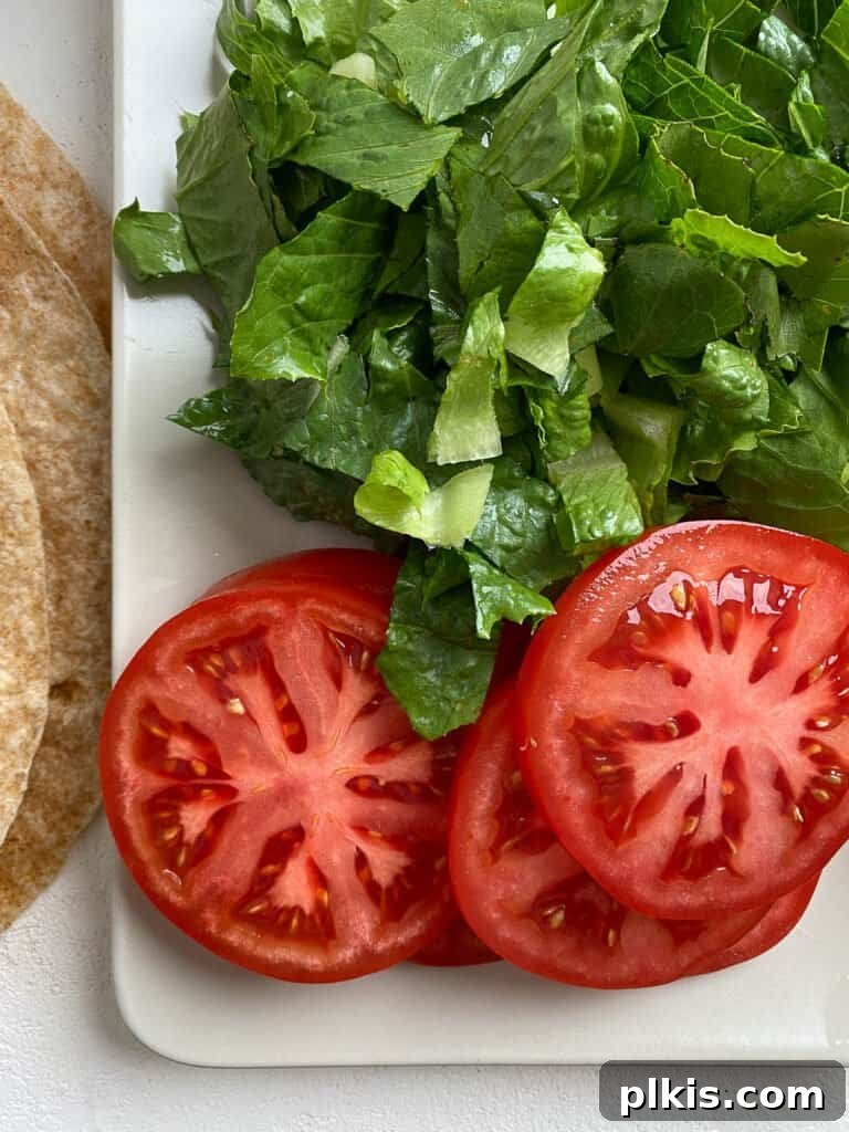 Flavor-Packed Cauliflower Wraps BBQ or Buffalo 4 Freshly sliced tomatoes and vibrant spinach laid out on a clean white cutting board, ready to be added as a delicious and healthy filling for vegan wraps.