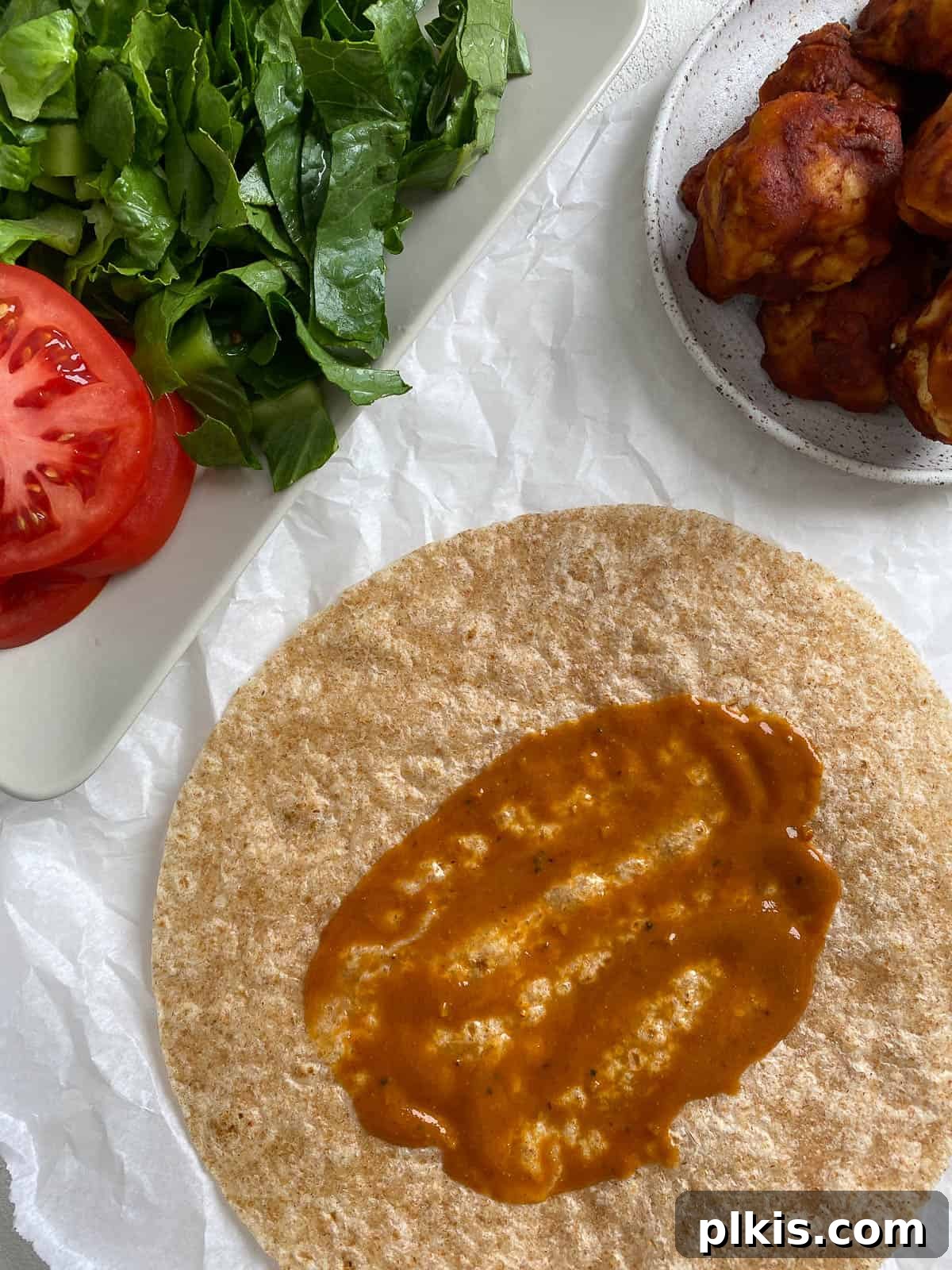 Flavor-Packed Cauliflower Wraps BBQ or Buffalo 6 Process shot showing a tortilla evenly coated with a rich, savory BBQ sauce, creating the perfect base for the flavorful cauliflower and fresh vegetable fillings.