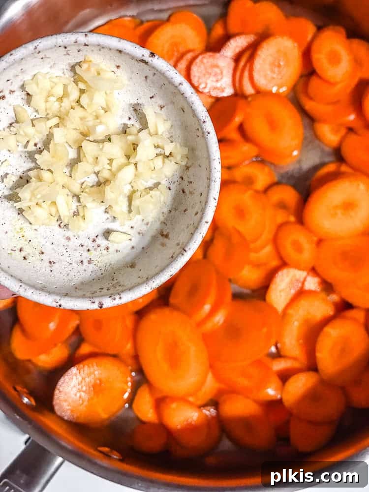 Golden Glazed Carrots 4 Process shot of minced garlic being added to a pan with carrots.