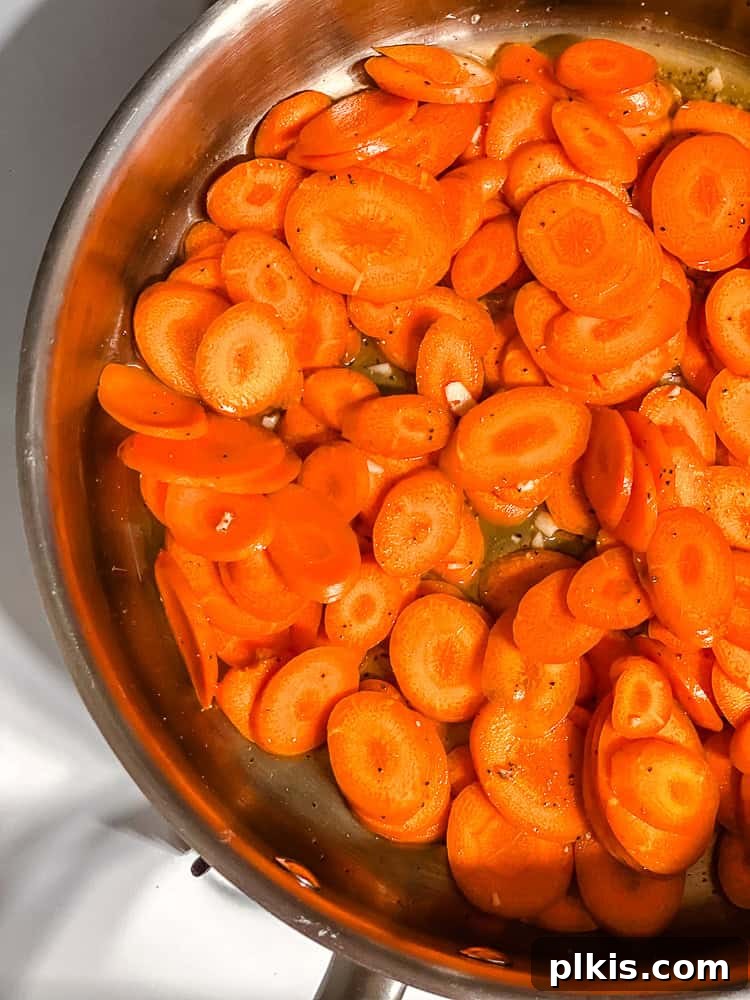 Golden Glazed Carrots 6 Process shot of carrots actively cooking and caramelizing in a pan with oil.