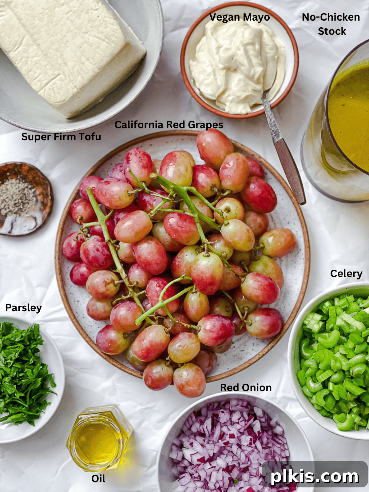 ingredients for Vegan Chicken and California Grape Salad measured out on a white surface, highlighting fresh grapes, celery, red onion, and tofu