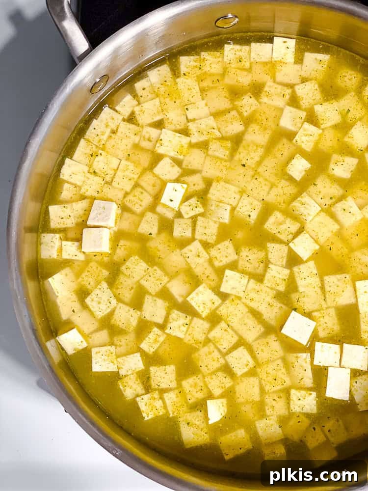 process shot showing tofu cooking in pan, simmering in stock