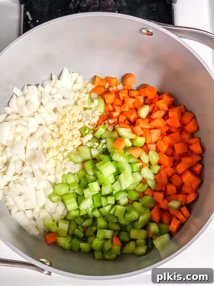 Sunshine Lemon Orzo Soup 4 Process shot showing a medley of diced onions, carrots, and celery sautéing in a pot with olive oil.