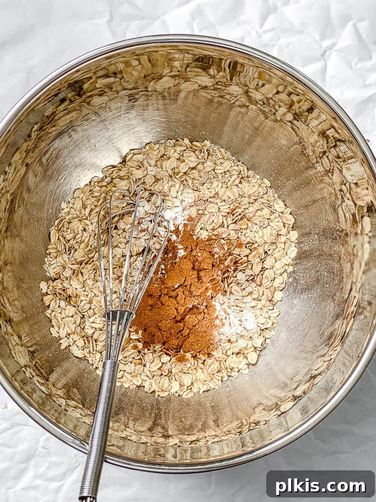 Warm Spiced Carrot Cake Baked Oats 4 The initial step in preparing Carrot Cake Baked Oats, showing dry ingredients being mixed in a large bowl.