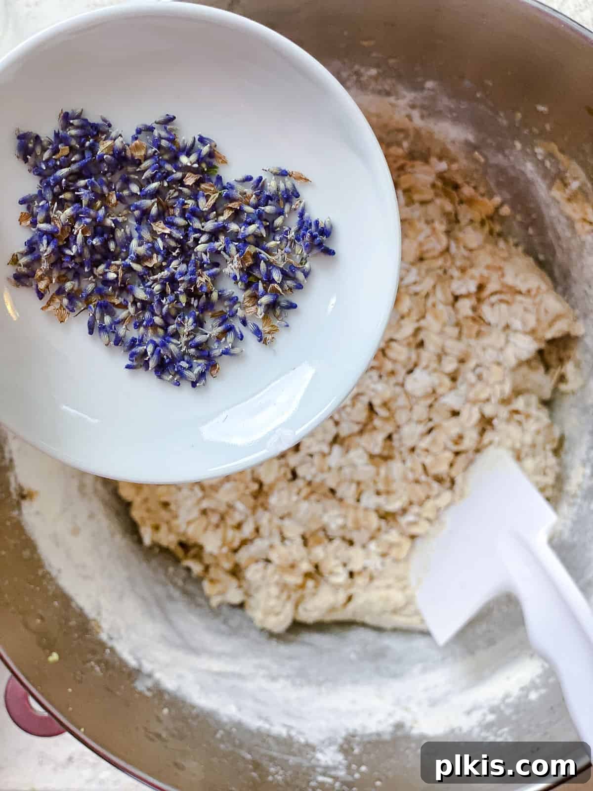 Adding Lavender to Dough Process of adding dried lavender flowers to cookie dough in a mixing bowl.