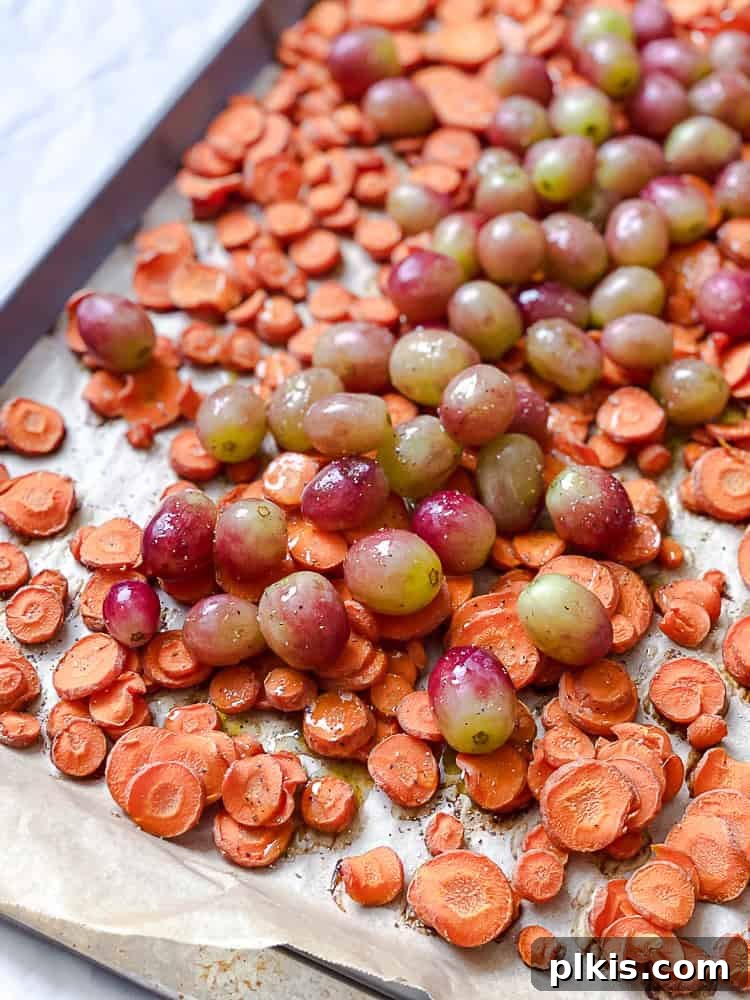 California Carrot & Grape Medley 5 Process shot showing red California grapes added to partially roasted carrots on a baking sheet, ready for further roasting.