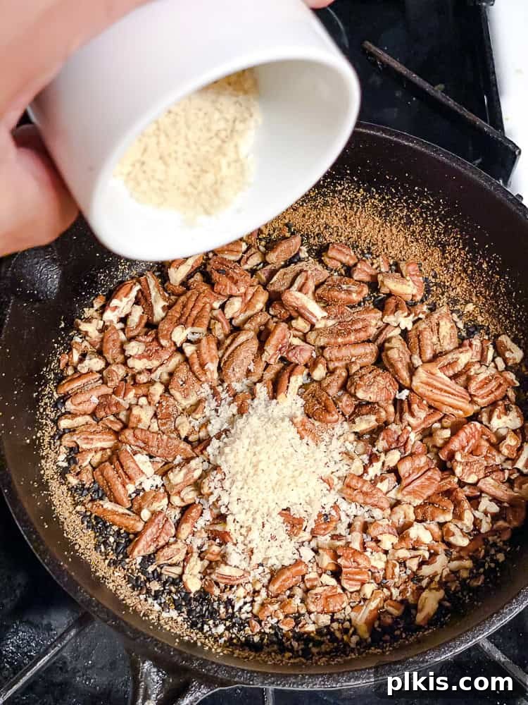 California Carrot & Grape Medley 7 Process shot showing cumin, coriander, and panko bread crumbs being added to the toasted nuts and sesame seeds in a pan, ready for mixing.