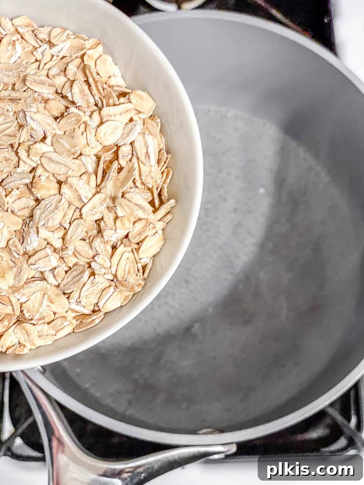 Cozy Autumn Pumpkin Oatmeal 4 Process shot illustrating the addition of rolled oats into a saucepan.