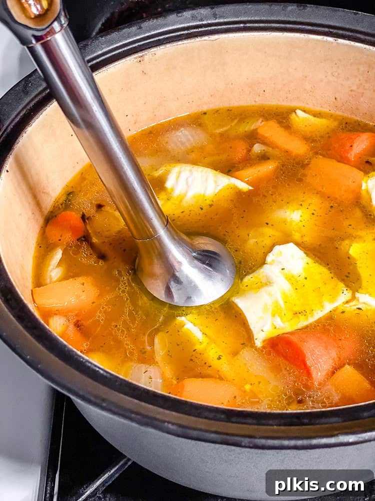 Golden Harvest Bisque 7 process shot showing using an immersion blender to blend the soup in the pot