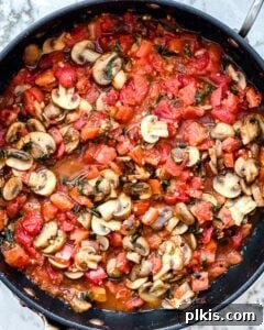Fiery Basil Tomato Delight 6 Process of cooking completed Spicy Tomato Basil Pasta, tossed in a black pan with sauce, ready for serving.