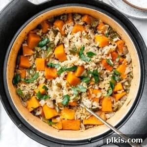A top-down view of a large pot filled with creamy Easy Pumpkin Rice, garnished with fresh herbs.