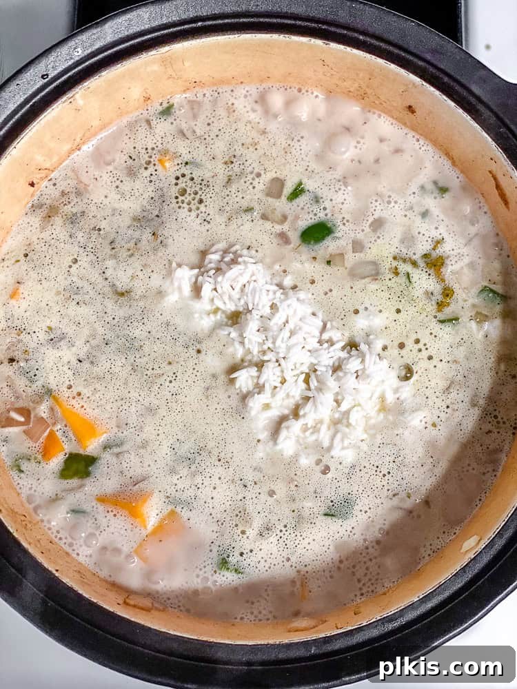Process shot of the Easy Pumpkin Rice cooking, covered with a lid, after adding rice and bringing to a simmer.