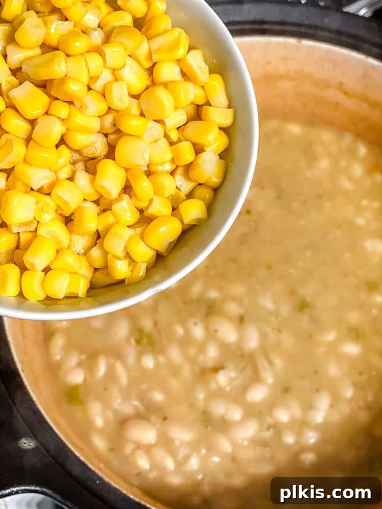 Creamy Plant-Based White Bean Chili 7 process shot showing adding corn to pot