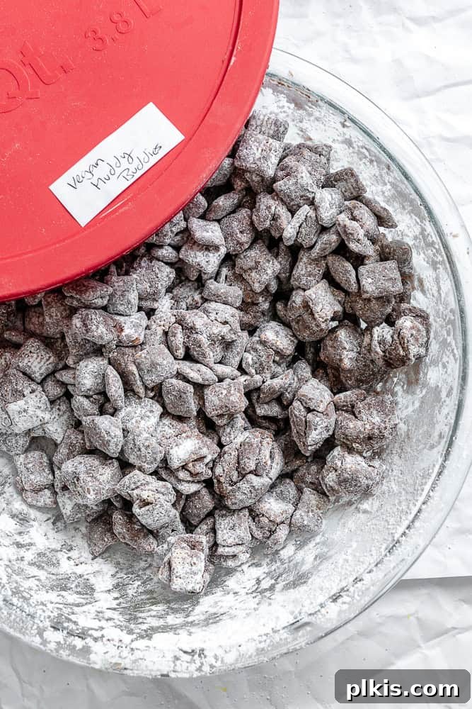 Close-up of Easy Muddy Buddies [Puppy Chow] stored in a clear, airtight container, emphasizing their make-ahead convenience and ideal preservation.