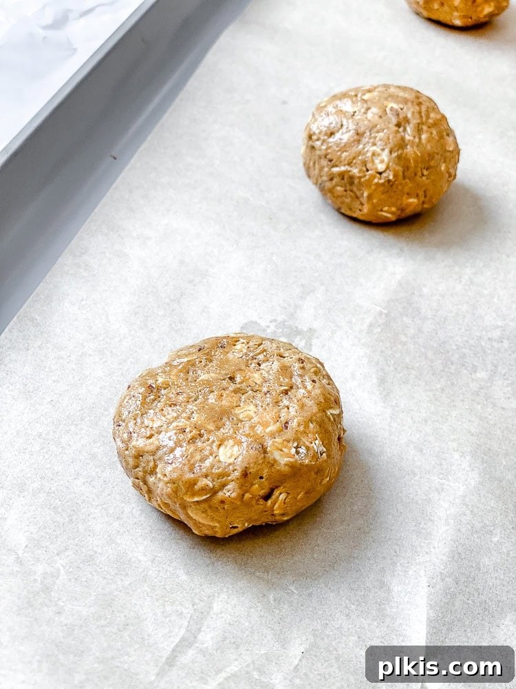 Cozy Gingerbread Oatmeal Cookies 7 Process shot demonstrating neatly scooped cookie dough portions arranged on a baking sheet lined with parchment paper, prepared for baking.
