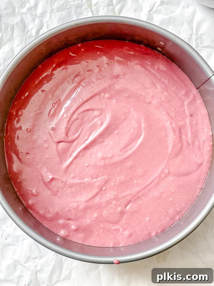 Plant-Based Red Velvet Perfection 6 Process shot showing vibrant red vegan red velvet cake batter poured into a prepared springform cake pan, ready for baking.