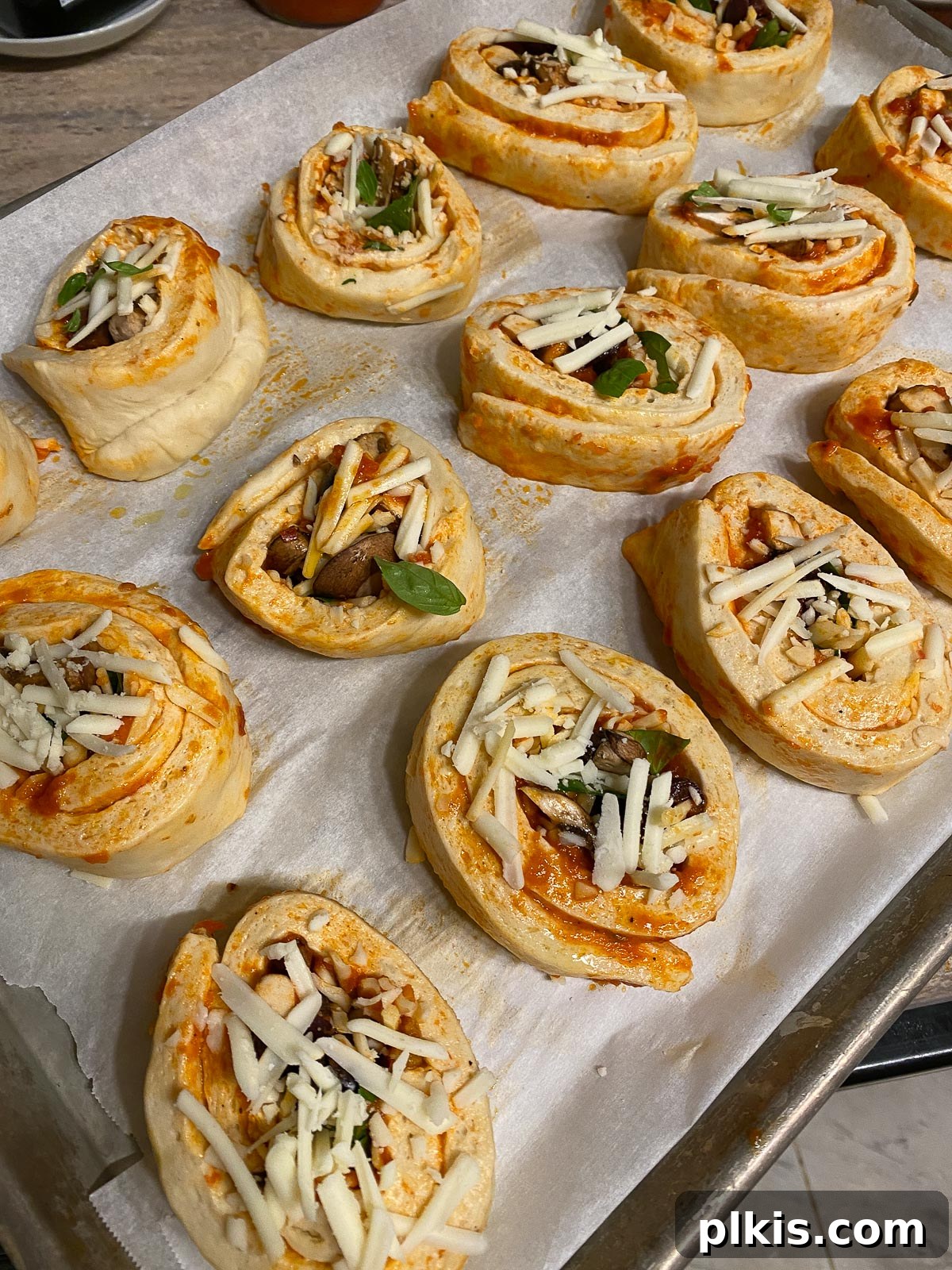 Unbaked vegan pizza rolls neatly arranged on a baking sheet, ready to go into the oven.