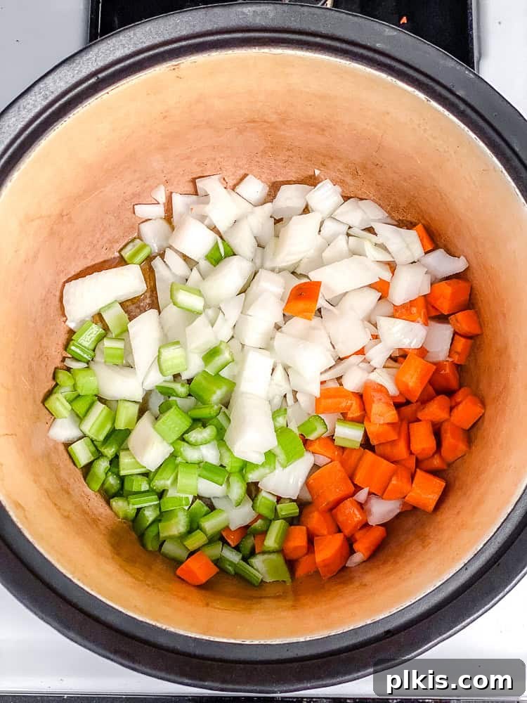 Sunshine Lentil Soup 4 Process shot showing a large pot on the stovetop with chopped onions, carrots, and celery sautéing in olive oil until lightly browned.